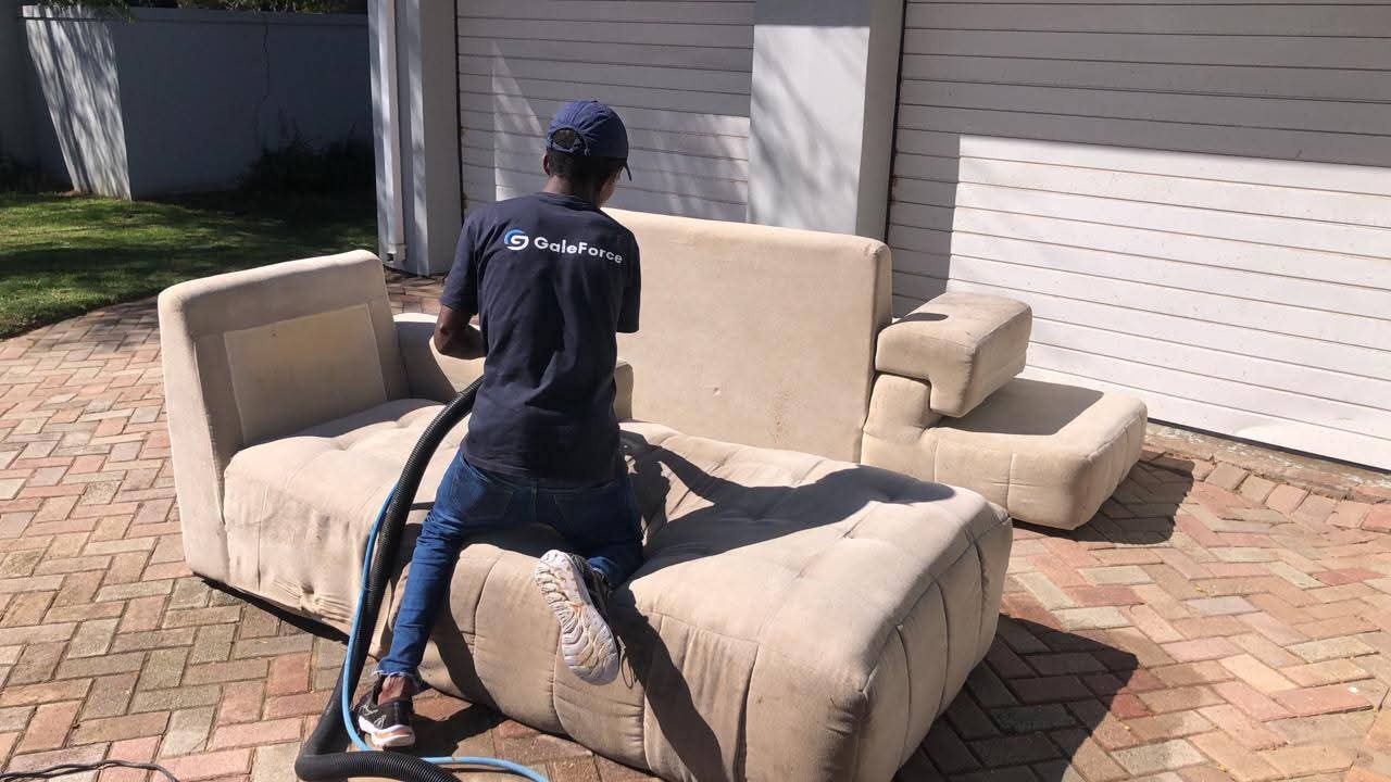 GaleForce worker cleaning couch outdoors